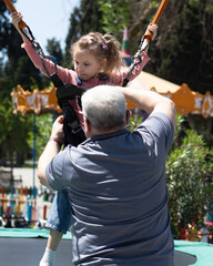 Father helps a daughter prepare for a bungee trampoline ride at an amusement park, security check....