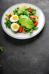 Avocado salad, boiled egg, tomato, green leaf lettuce, vegetable dish fresh delicious gourmet food background on the table rustic food top view copy space keto and paleo diet vegetarian food