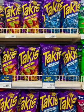 Brightly colored Takis snack bags in Fuego and Blue Heat flavors displayed on supermarket shelves with new arrival labels.