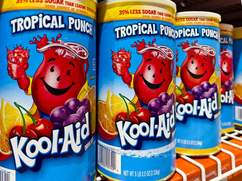Kool-Aid Tropical Punch flavor in bright blue canisters, featuring fruit illustrations and classic red mascot.