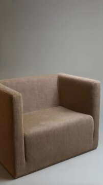 Isolated single seat armchair with beige corduroy upholstery against neutral backdrop in studio lighting, cozy modern furniture.