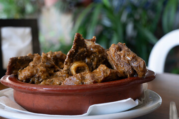 A bowl of goat meat with a white napkin on top. The goat meat is browned and has a lot of seasoning.