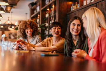 Cheerful female friends enjoying conversation at a bar counter