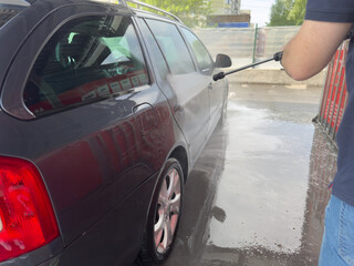 Closeup of male driver washing his car with contactless high pressure water jet
