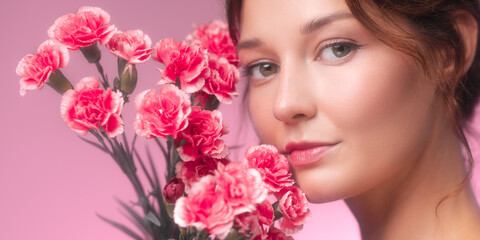 Naklejka premium Romantic Portrait Banner Of Woman Posing With Pink Carnations And Flawless Skin