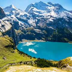 Amazing view of Switzerland Oeschinensee. Turquoise blue alpine lake amidst the snow capped mountains. Summer sunny day in Swiss Alps. Great tourist attraction for active sport and hiking