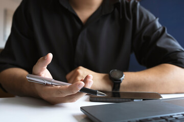Businessman Holding Pen with Laptop and Smartphone on Desk