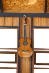 Classical Guitar hanging on the wall of the house with a blank white channel window.