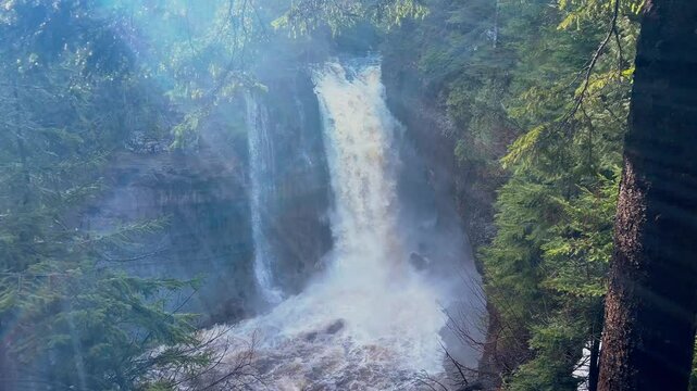 Miners Falls at Pictured Rocks National Lakeshore in Michigan during sunrise with cascading water and glowing forest scenery.