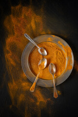 A metal plate with three spoons, embellished with bright yellow turmeric powder, which adds a warm and golden touch to the environment.