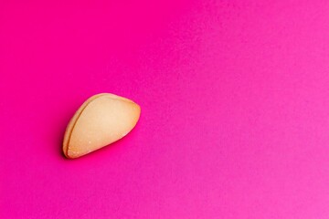 Fortune cookie against a pink background