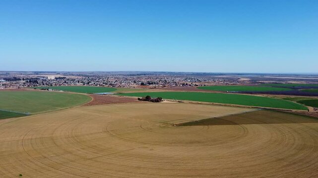 Aerial view of circular agricultural fields with a town in the distance under a clear blue sky south africa