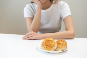 Gluten allergy, asian young woman, girl refusing to eat, looking at bread slice on plate in breakfast food meal on table at home, having a stomach ache. Gluten intolerant and Gluten free diet concept.