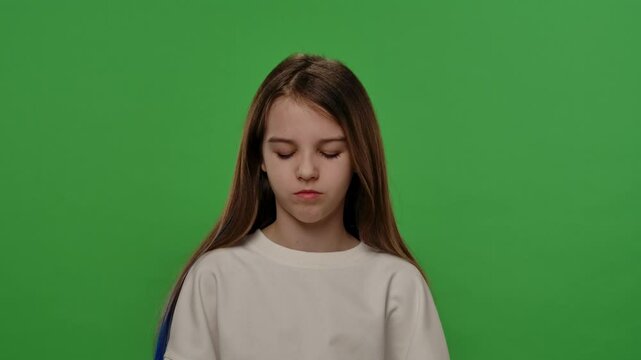 Teenage girl posing at camera with bored sleepy face, tired expression, isolated on chroma key green screen studio background mockup. Slow motion