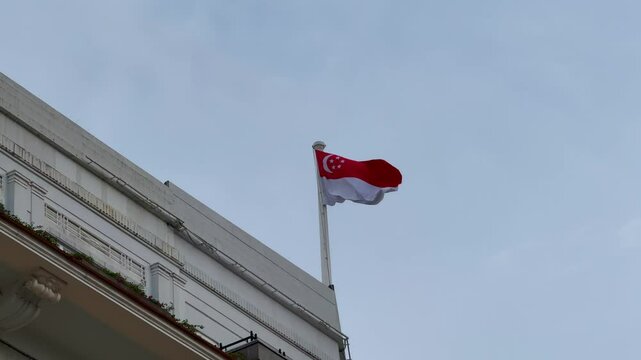 Singapore National Flag Flying on Government Building Against Clear Sky &ndash; Symbol of National Pride and Identity