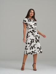 Fototapeta premium Elegant woman showcases fashion in a stylish studio setting with beautiful floral design