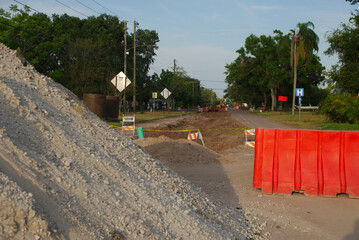 Street Construction Zone with Barriers and Equipment Near Trees. Construction site on a residential...