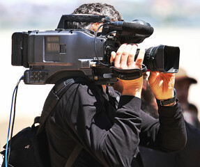 Cámara de tv grabando con su cámara al hombro para un medio de comunicación de televisión