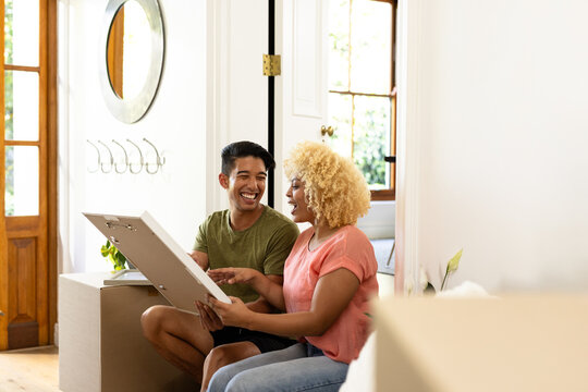 Young diverse couple unpacking and laughing together in new home, enjoying moment