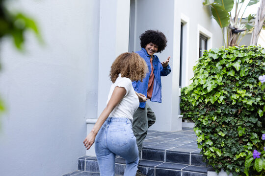 Young friends laughing and greeting each other outside modern home