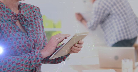 Image of lights and graphs over hands of caucasian businesswoman working on tablet