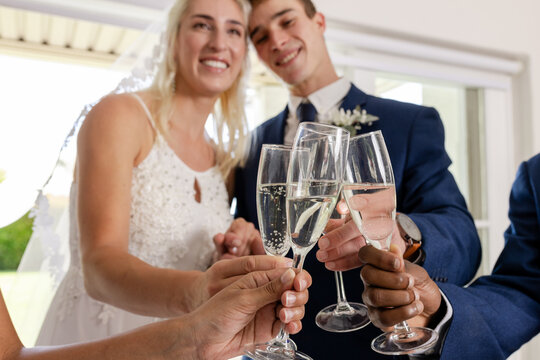 Newlywed couple toasting with friends, celebrating joyful wedding moment together