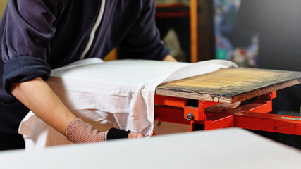 silk screen textile printery. manual screen printing. white t-shirt in a male hands ready for printing. selective focus