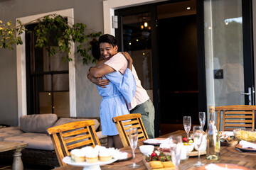 Fototapeta premium Diverse friends hugging joyfully at outdoor gathering with cupcakes and champagne on table