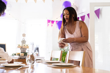Mother setting table with plates and decorations for festive religious celebration, at home