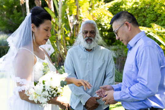 Exchanging rings, bride and groom with officiant during outdoor senior wedding ceremony - Powered by Adobe