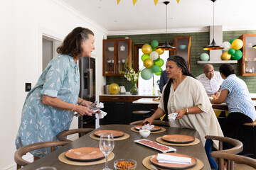 Seniors in modern kitchen preparing table for celebration, talking together