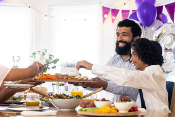 Diverse family celebrating religious occasion at home, sharing food and enjoying, copy space