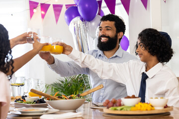 Celebrating religious occasion, diverse family toasting with drinks around festive table, at home