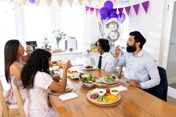 Diverse family celebrating religious milestone with festive meal and decorations at home