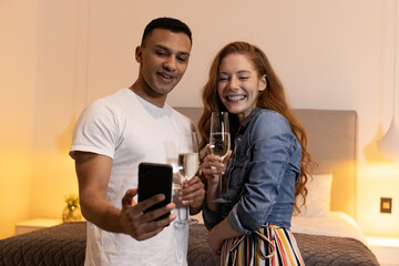 Celebrating at home, couple taking selfie with champagne glasses, smiling joyfully