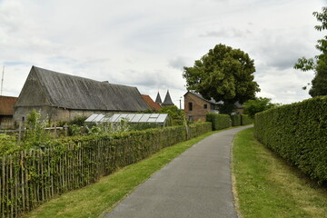 Route étroite de campagne sous un ciel gris près de la ferme du château-fort à Écaussinnes...