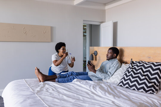 Relaxing at home, friends enjoying conversation while using smartphone on bed