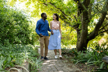 Couple walking hand in hand on garden path, enjoying nature and conversation