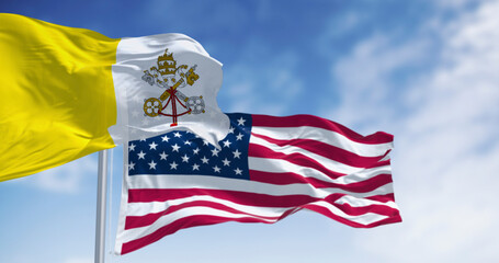 Vatican city flag waving in the wind with the American flag on a clear day