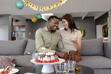 Couple celebrating birthday at home, enjoying cake and sharing joyful moment