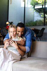Obraz premium Couple embracing on sofa at home, enjoying peaceful and loving moment together