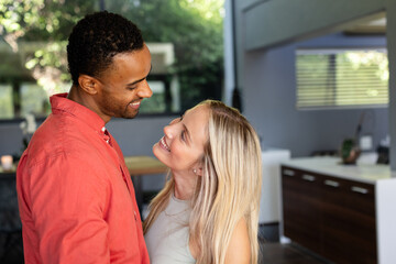 Couple smiling and embracing in modern kitchen, enjoying joyful moment together