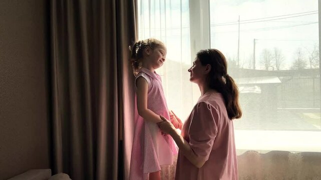Sweet mother-daughter moment. 4 years old blonde girl and her mom share a tender nose to nose kiss. Heartwarming display of unconditional love and family bonding