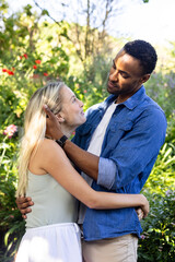 Fototapeta premium Couple embracing in garden, smiling and enjoying romantic moment together