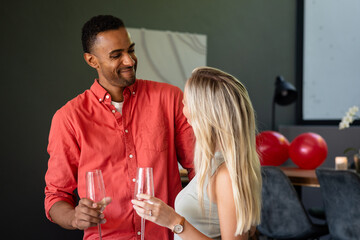 Couple celebrating with champagne glasses, sharing joyful moment at home