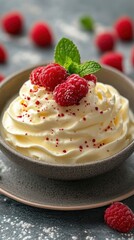 Delicious bowl of whipped cream topped with fresh raspberries and mint leaves against a textured backdrop