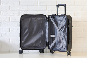 Black suitcase on white background. An open suitcase for traveling. Brick background.