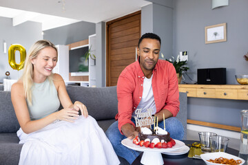 Celebrating birthday, man and woman enjoying cake with joyful expressions at home