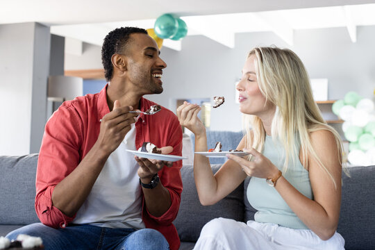 Naklejki Couple enjoying cake together on sofa, celebrating joyful moments at home