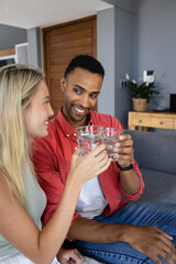 Couple toasting with glasses of water, smiling and enjoying time together at home